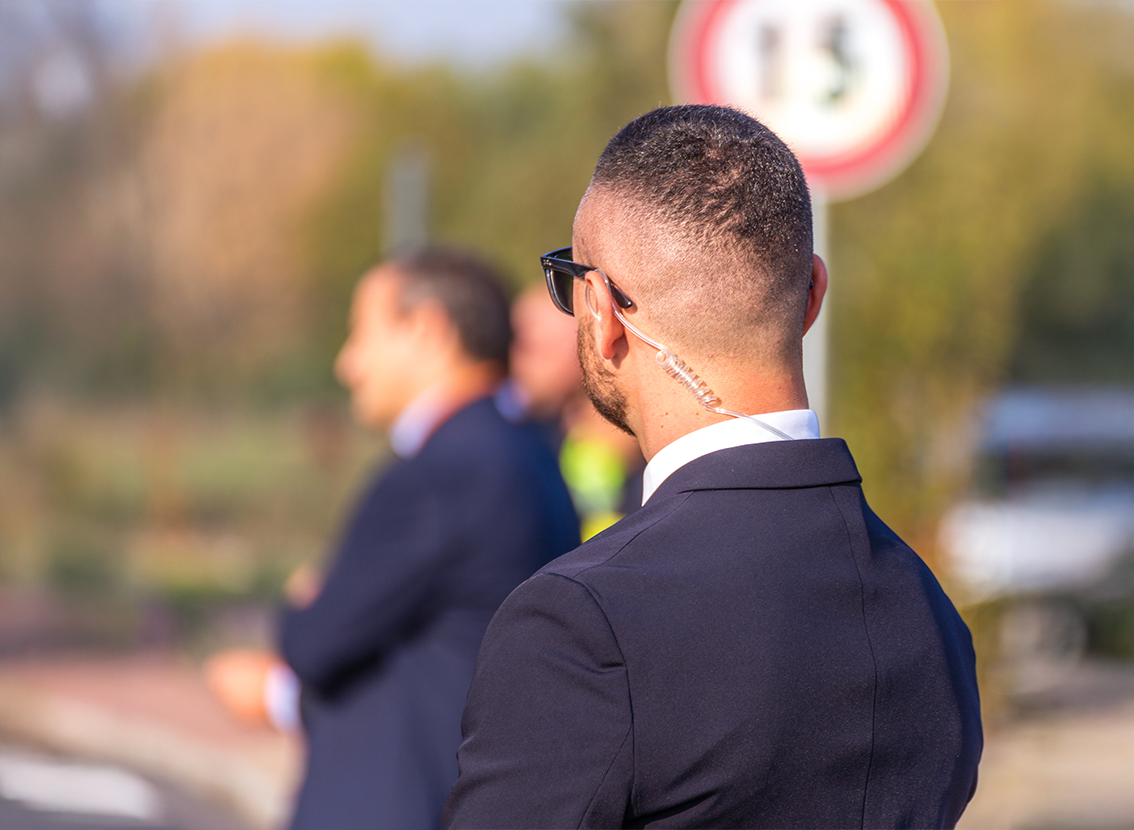 dw Security on public event. Secret guard service. Private bodyguard with earpiece standing among crowd. Safety of govern and business meeting. Secret service agent listening to his earpiece, side.